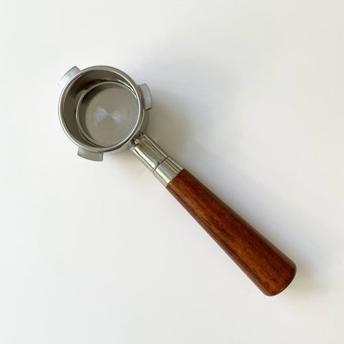 A bottomless portafilter with an almond solid wood handle and stainless steel basket.